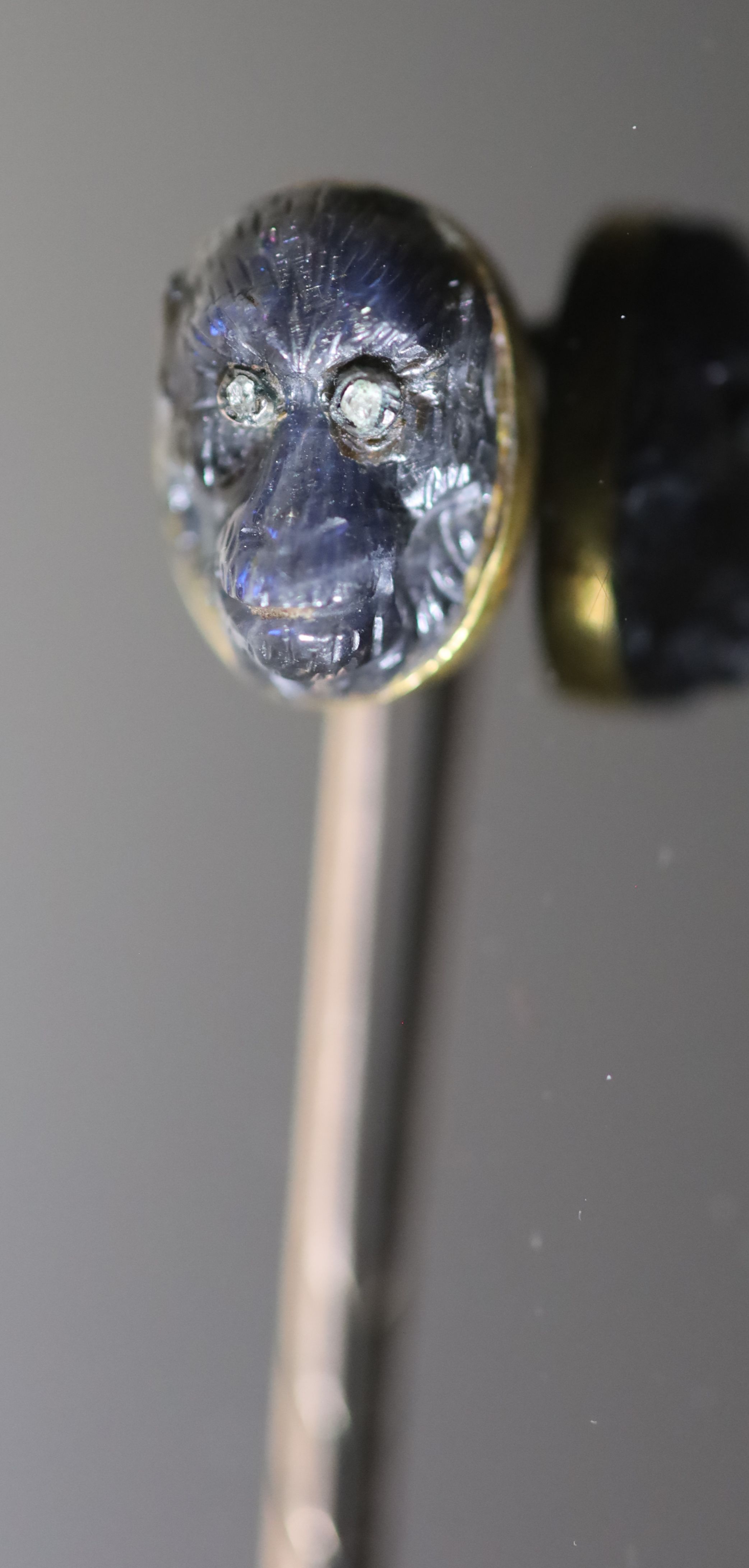 A Victorian gold mounted diamond set labradorite? stick pin, carved as the head of an ape,